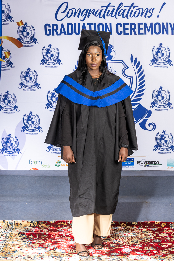 Graduate receives a certificate on stage during the graduation ceremony as faculty members look on.