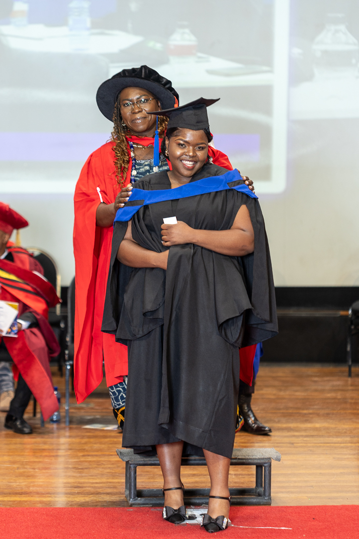 Graduate receives a certificate on stage during the graduation ceremony as faculty members look on.