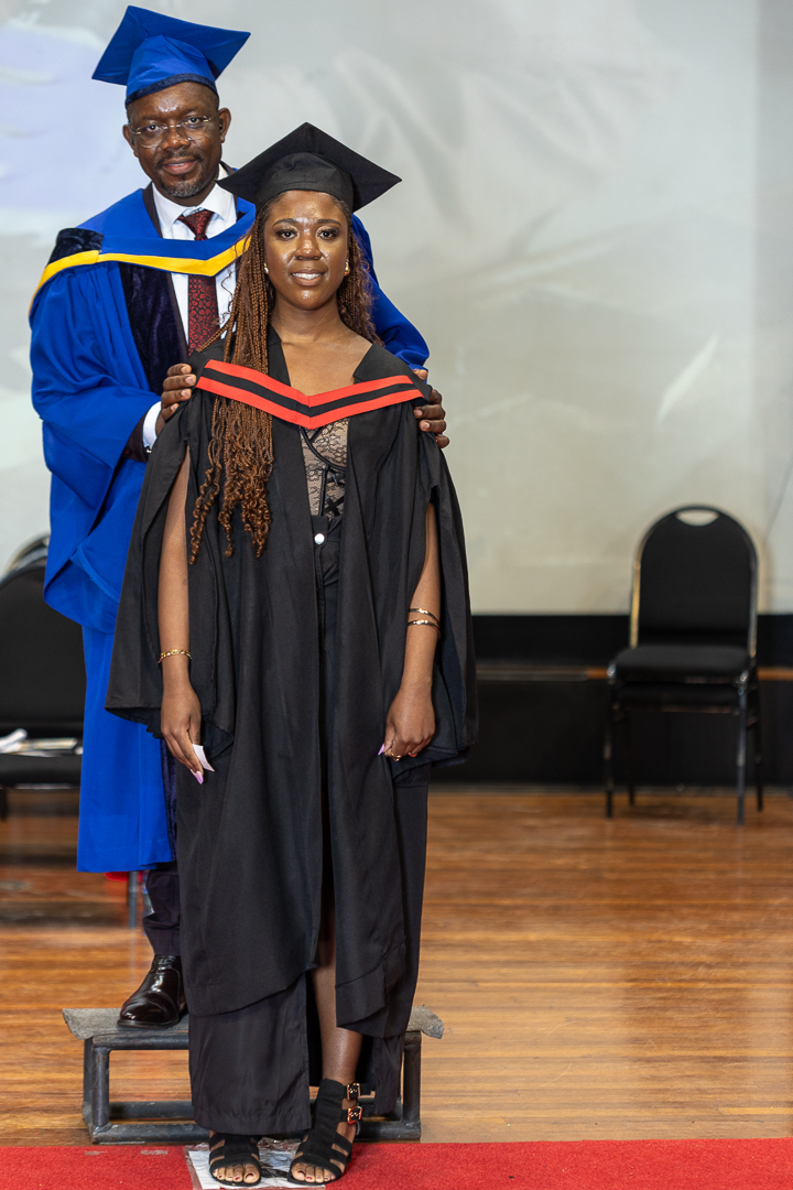 Graduate receives a certificate on stage during the graduation ceremony as faculty members look on.