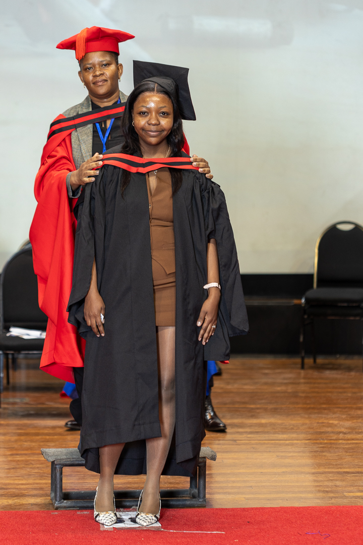 Graduate receives a certificate on stage during the graduation ceremony as faculty members look on.